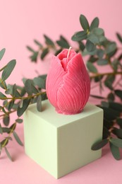 Photo of Beautiful flower shaped candle and leaves on pink background, closeup