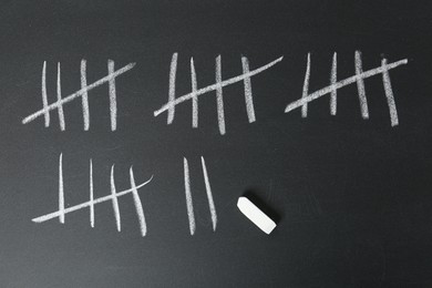 Photo of Counting days by drawing sticks with chalk on blackboard, top view