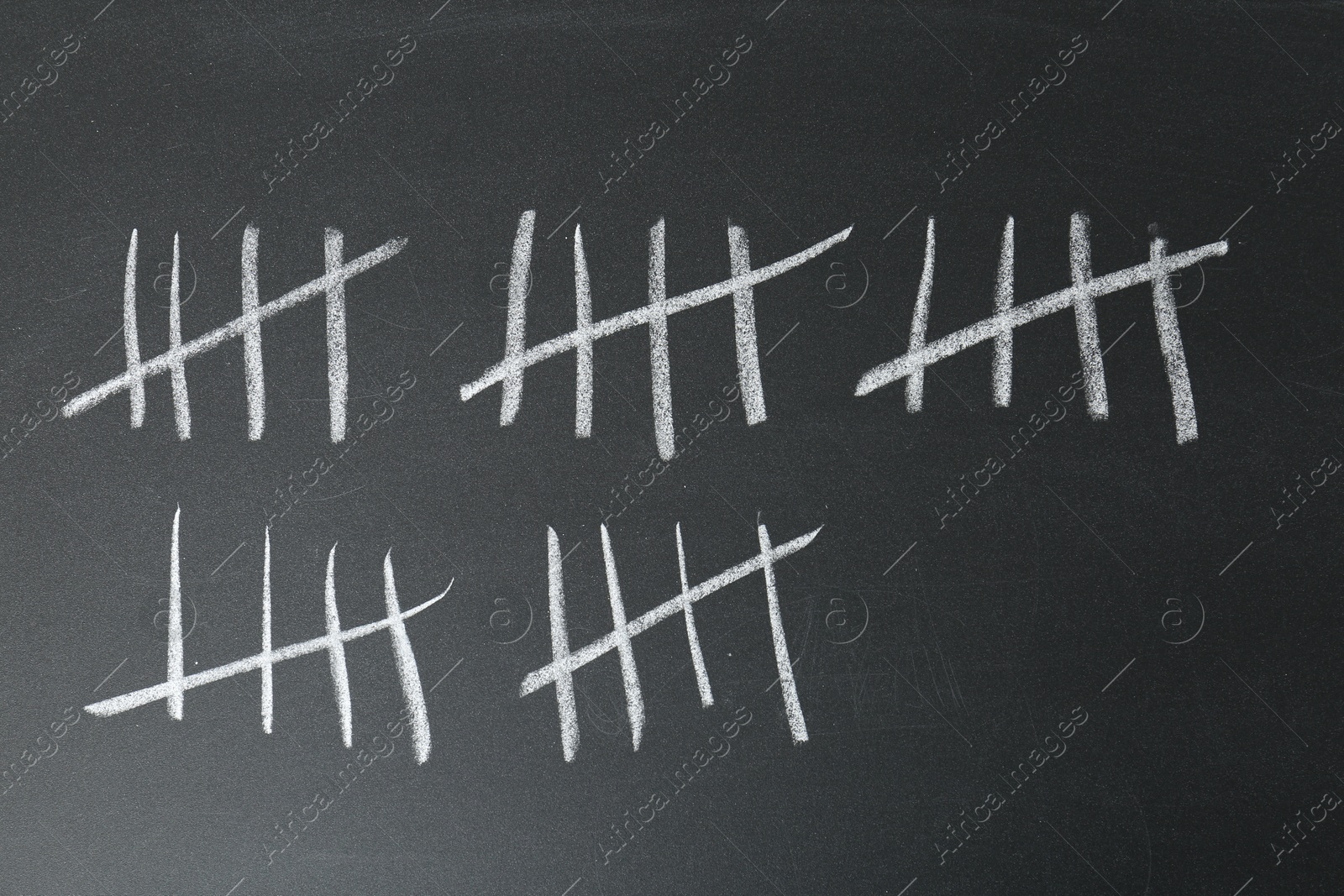 Photo of Counting days by drawing sticks with chalk on blackboard, closeup