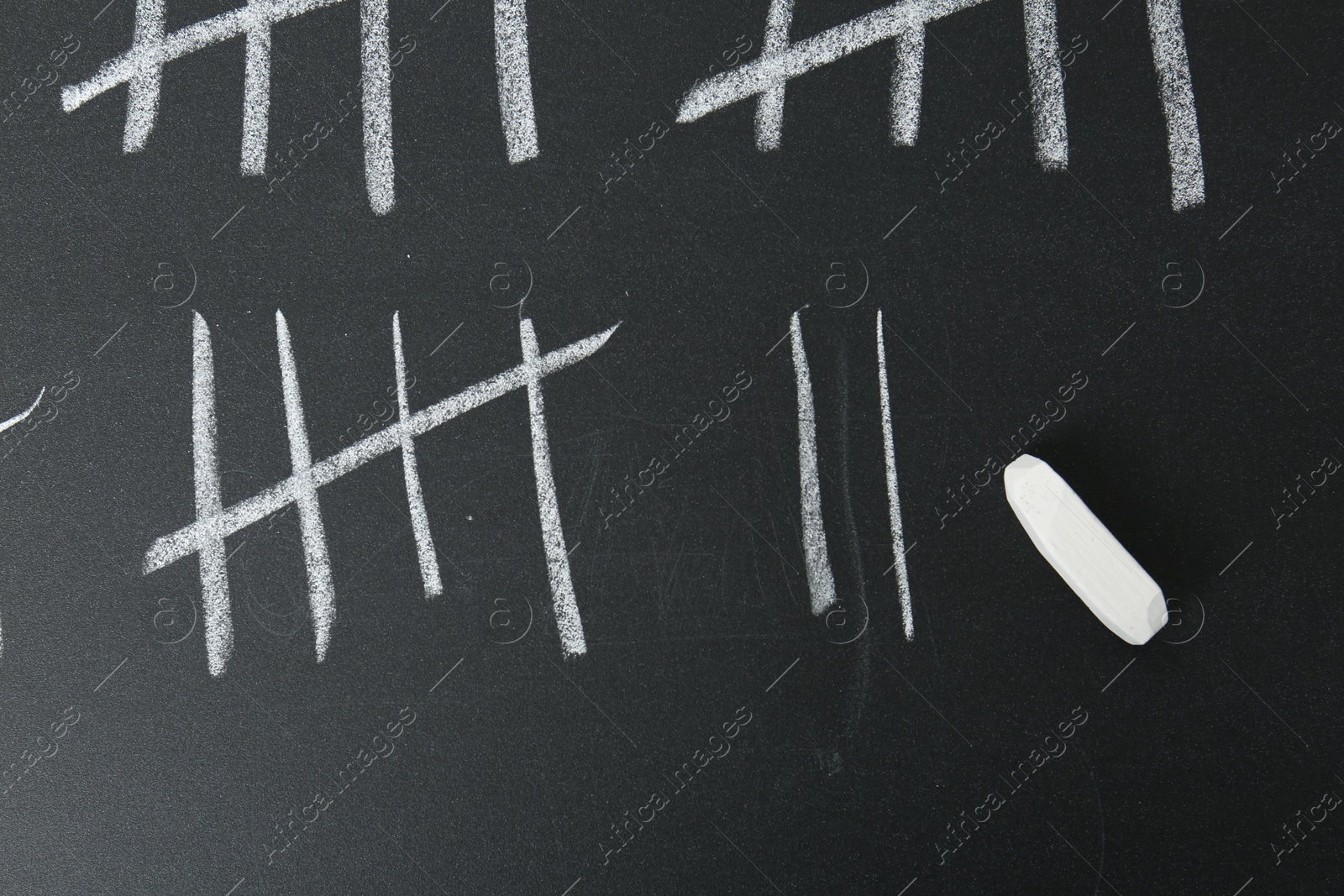 Photo of Counting days by drawing sticks with chalk on blackboard, top view