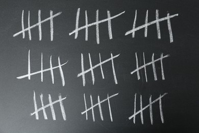 Photo of Counting days by drawing sticks with chalk on blackboard, closeup