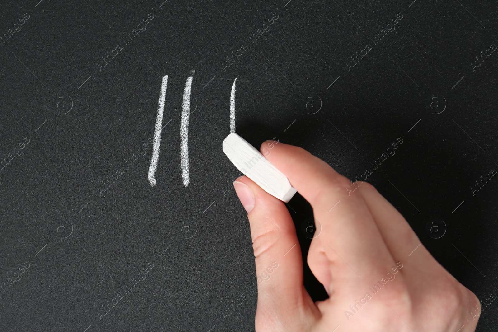 Photo of Woman counting days by drawing sticks with chalk on blackboard, closeup