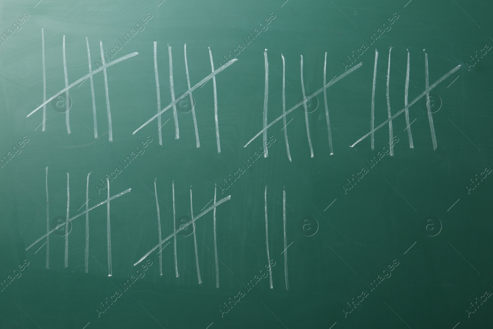 Photo of Counting days by drawing sticks with chalk on chalkboard, closeup