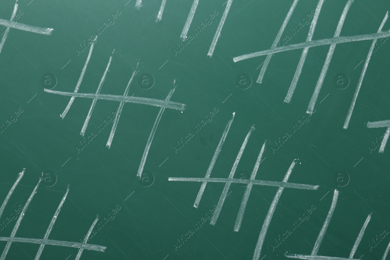 Photo of Counting days by drawing sticks with chalk on chalkboard, closeup