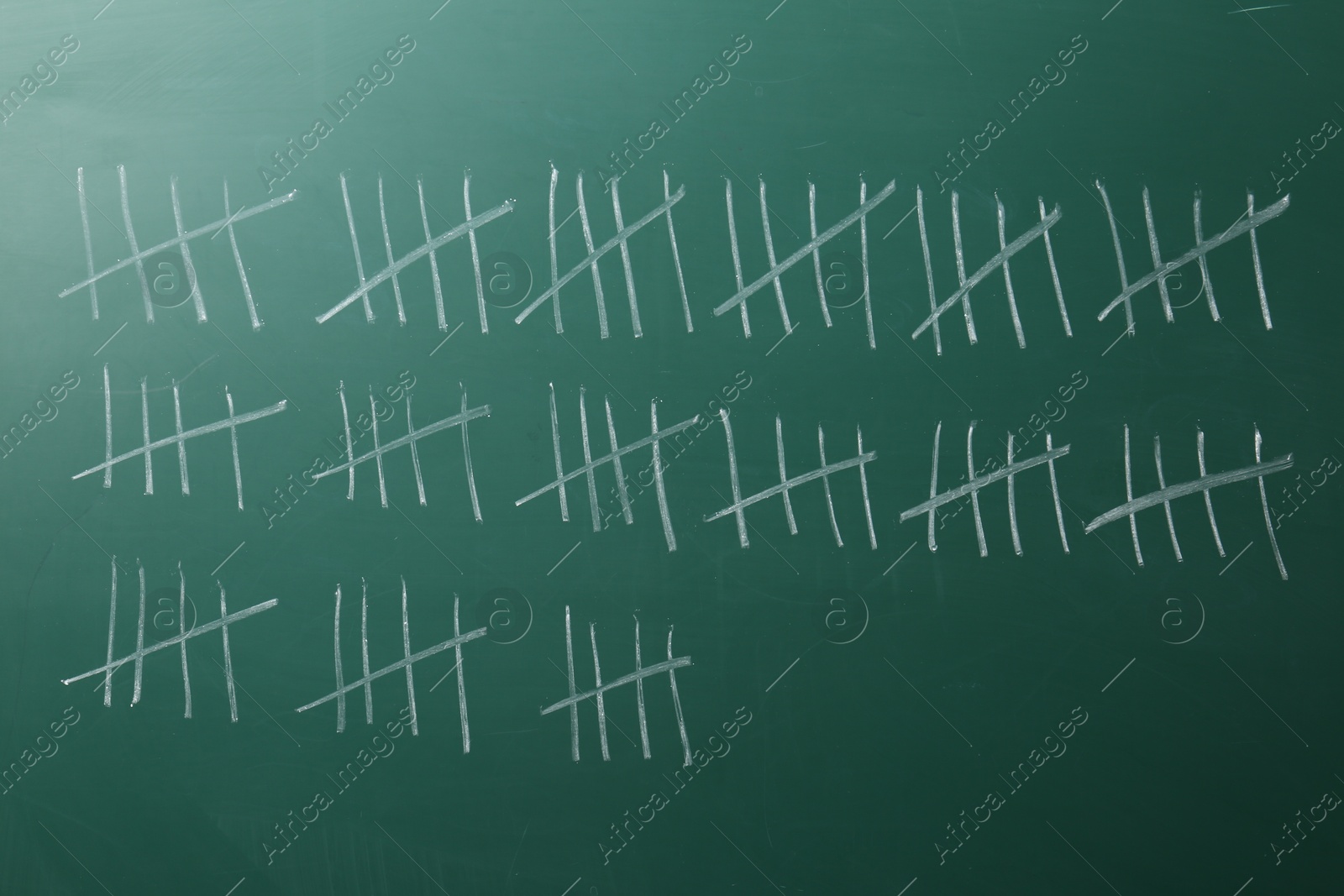 Photo of Counting days by drawing sticks with chalk on chalkboard, closeup