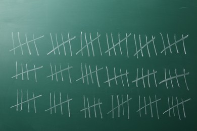 Photo of Counting days by drawing sticks with chalk on chalkboard, closeup