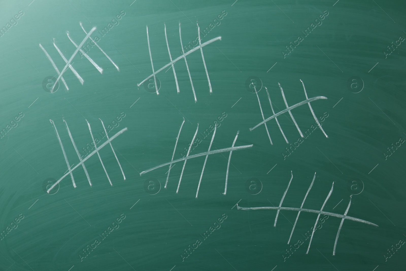 Photo of Counting days by drawing sticks with chalk on chalkboard, closeup