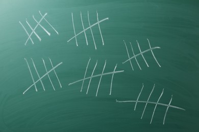 Photo of Counting days by drawing sticks with chalk on chalkboard, closeup