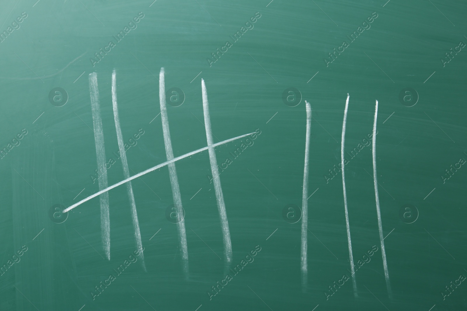 Photo of Counting days by drawing sticks with chalk on chalkboard, closeup