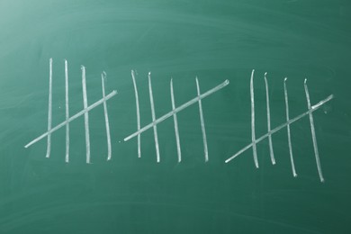 Photo of Counting days by drawing sticks with chalk on chalkboard, closeup