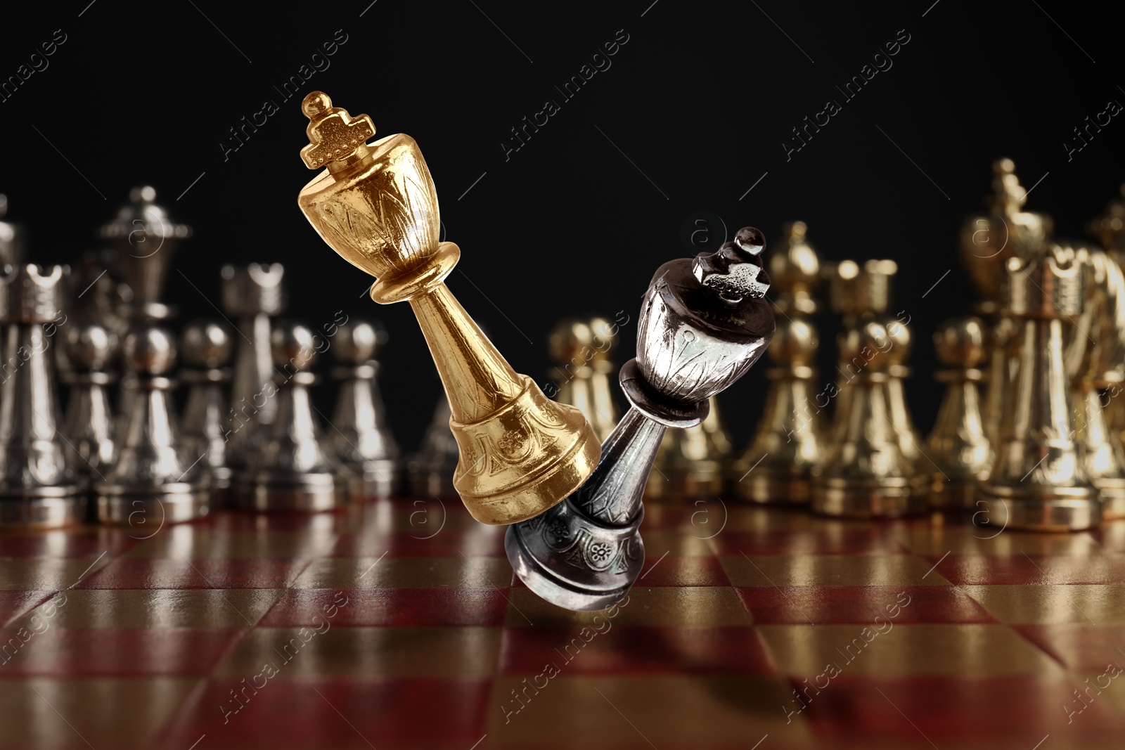 Image of Chess game. Golden king beating silver king in air over chessboard