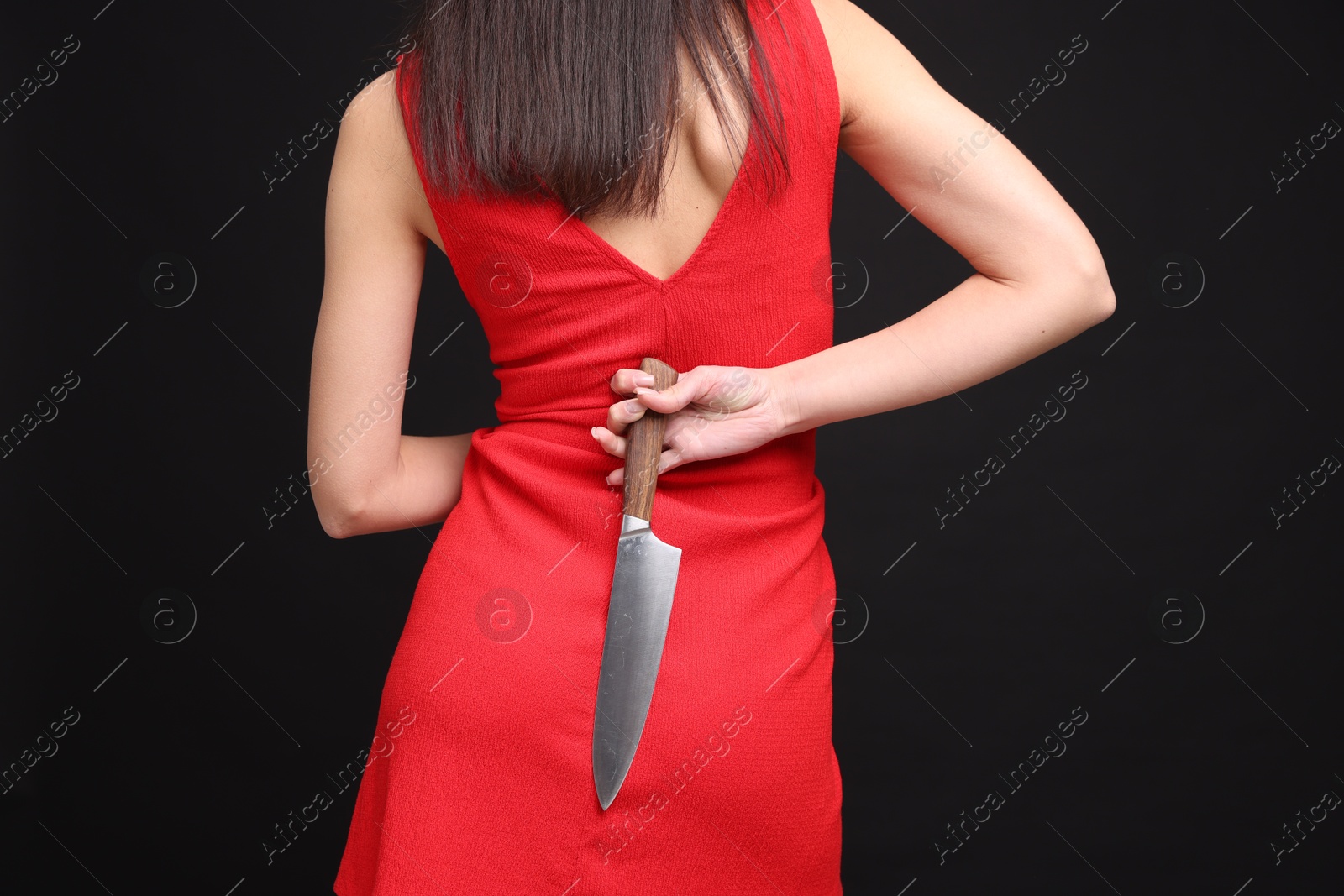 Photo of Businesswoman with knife behind her back on black background, closeup