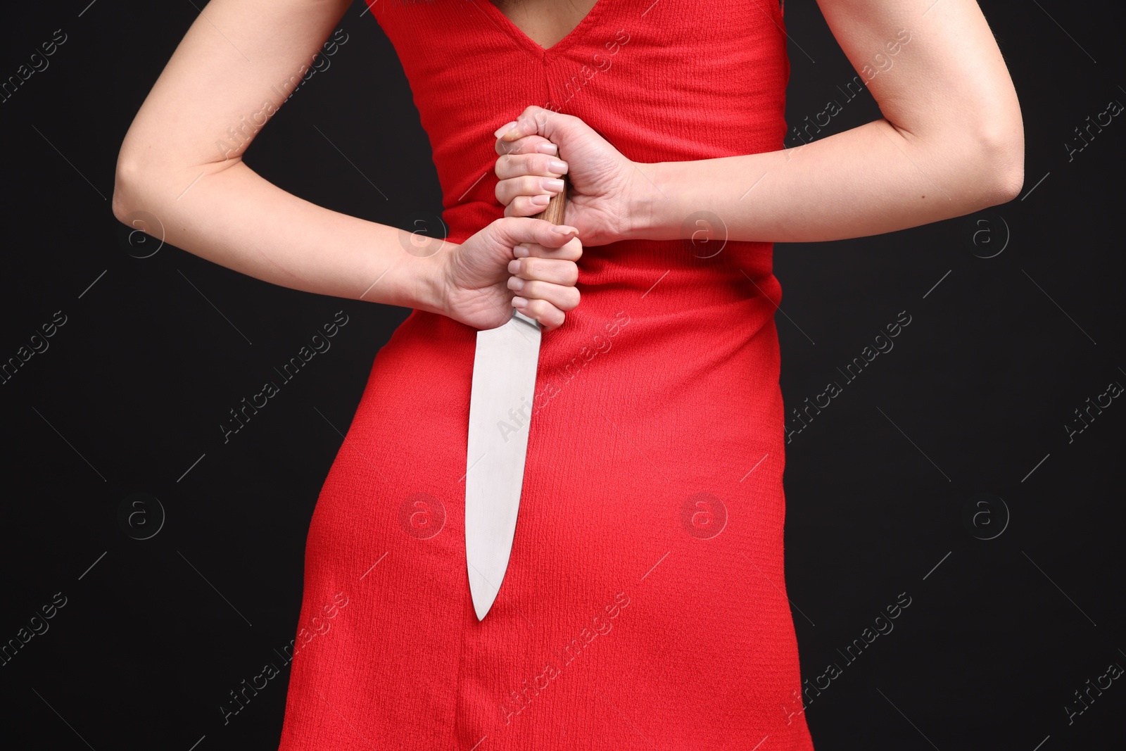 Photo of Businesswoman with knife behind her back on black background, closeup