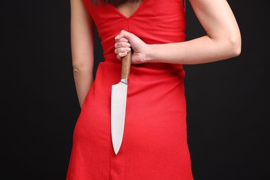 Photo of Businesswoman with knife behind her back on black background, closeup