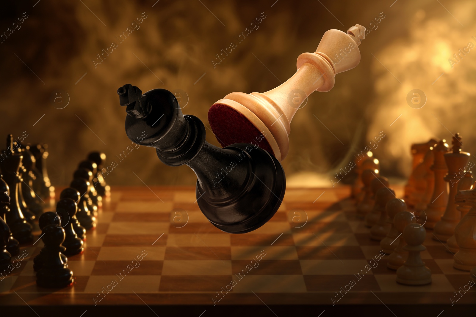 Image of Chess game. White king beating black king in air over chessboard