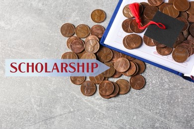 Image of Scholarship. Graduate hat, notebook and coins on light grey table