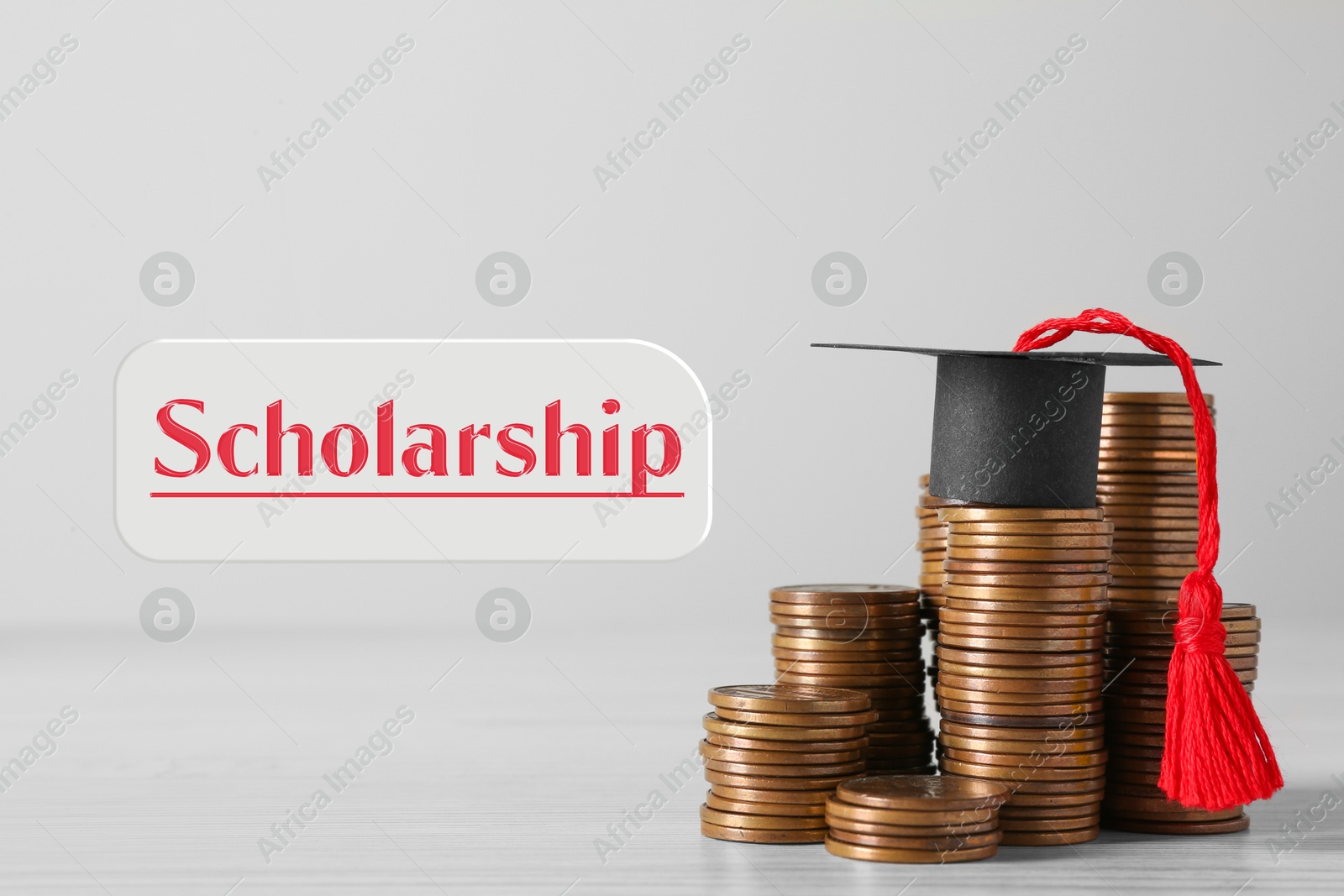 Image of Scholarship. Graduate hat and stacked coins on white wooden table