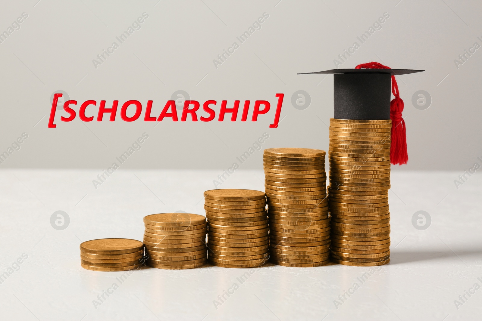 Image of Scholarship. Graduate hat and stacked coins on white table