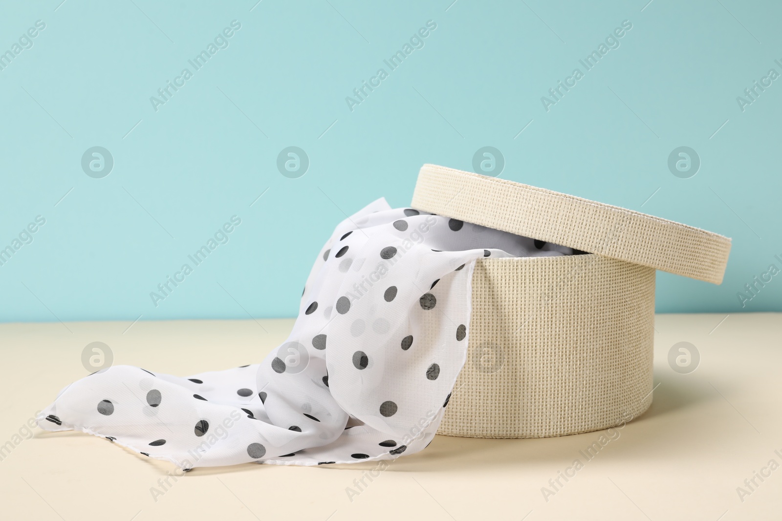 Photo of Dotted scarf in box on color background. Space for text