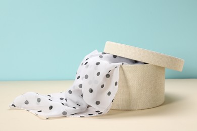 Photo of Dotted scarf in box on color background. Space for text