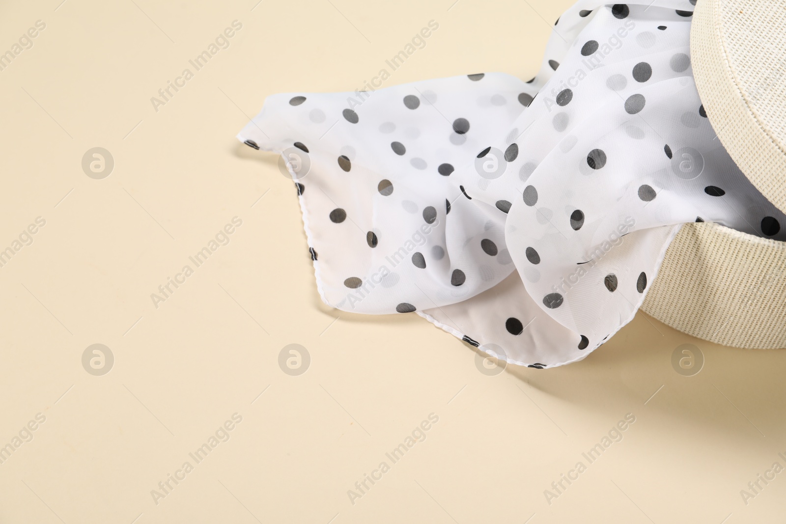 Photo of Dotted scarf in box on beige background, closeup. Space for text