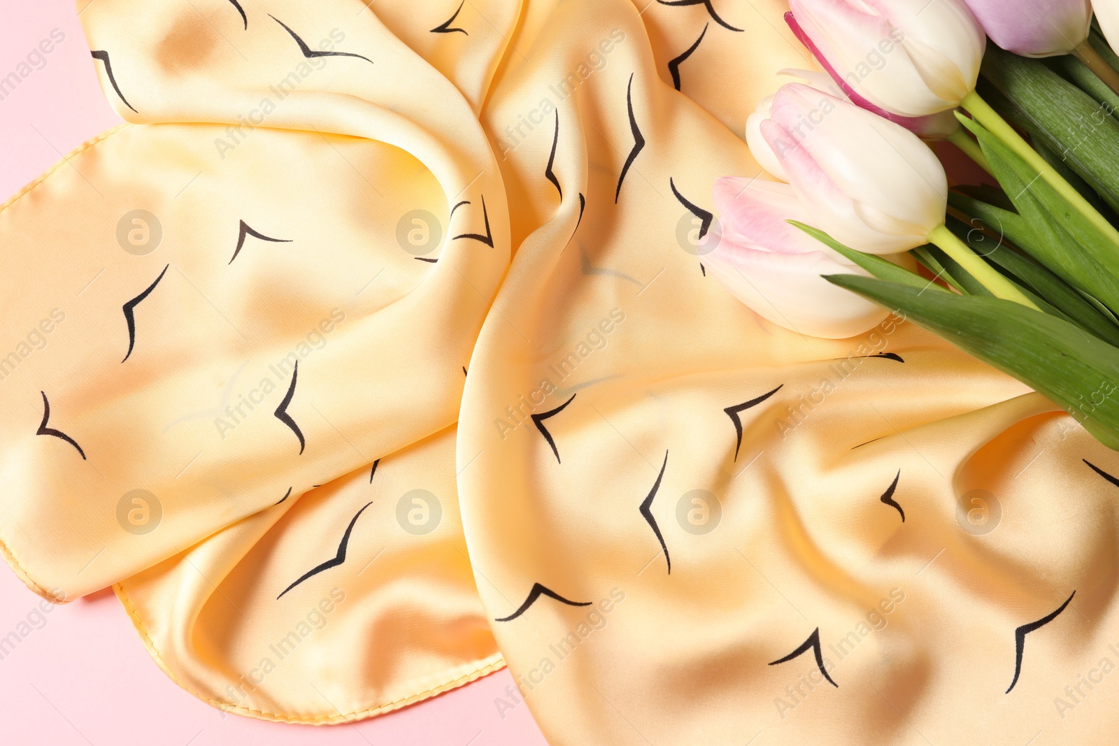 Photo of Beautiful scarf and tulips on light pink background, top view