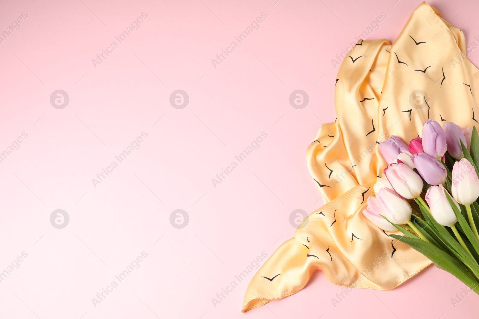 Photo of Beautiful scarf and tulips on light pink background, top view. Space for text