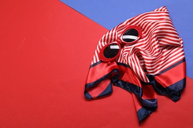 Photo of Beautiful striped scarf and sunglasses on color background, top view. Space for text