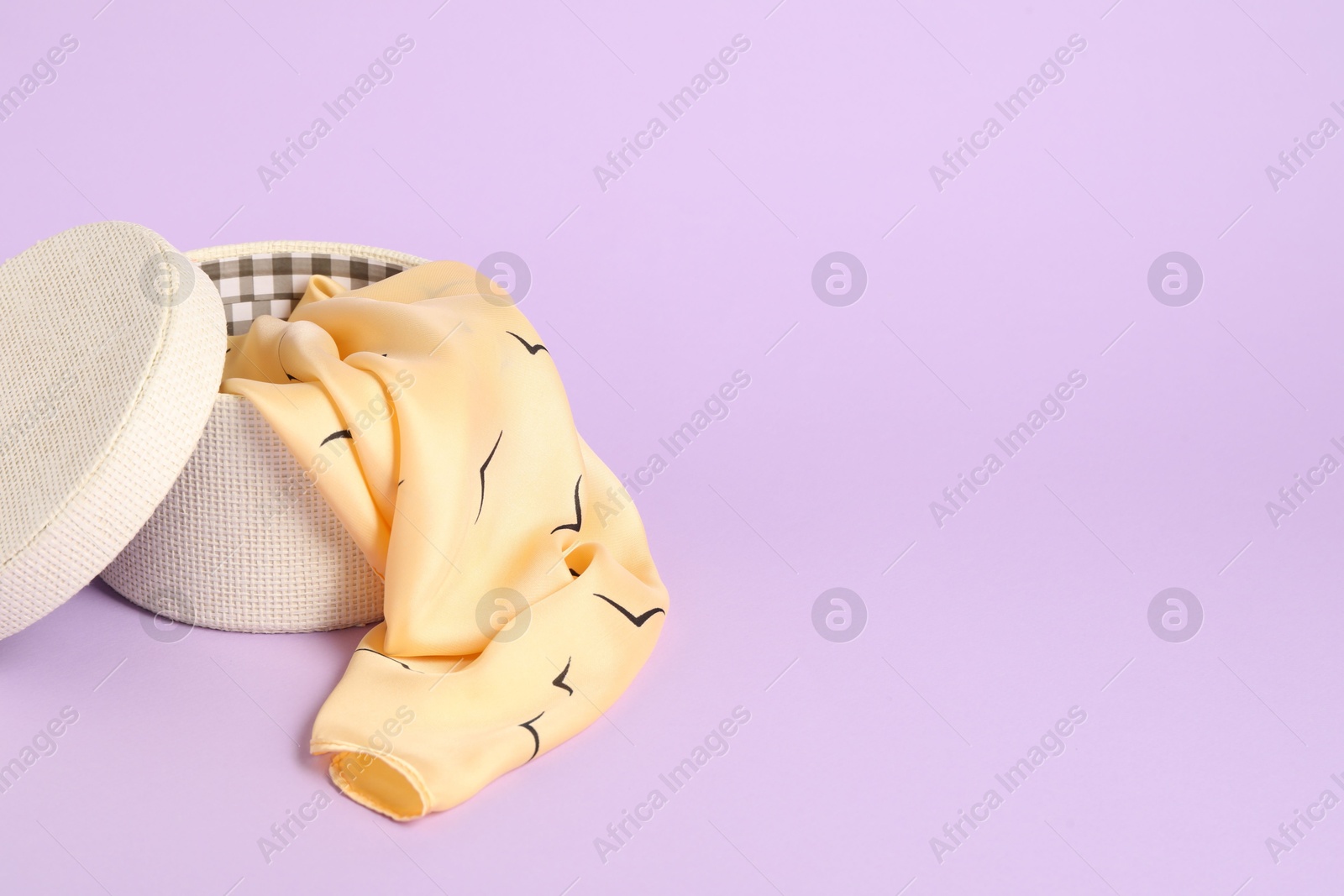 Photo of Beautiful scarf in box on lilac background. Space for text