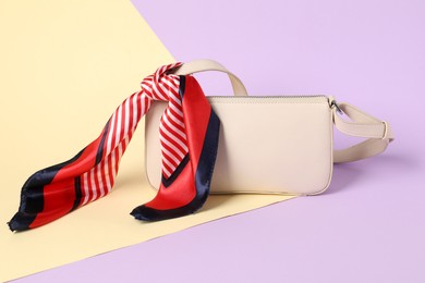 Photo of Handbag with striped scarf on color background