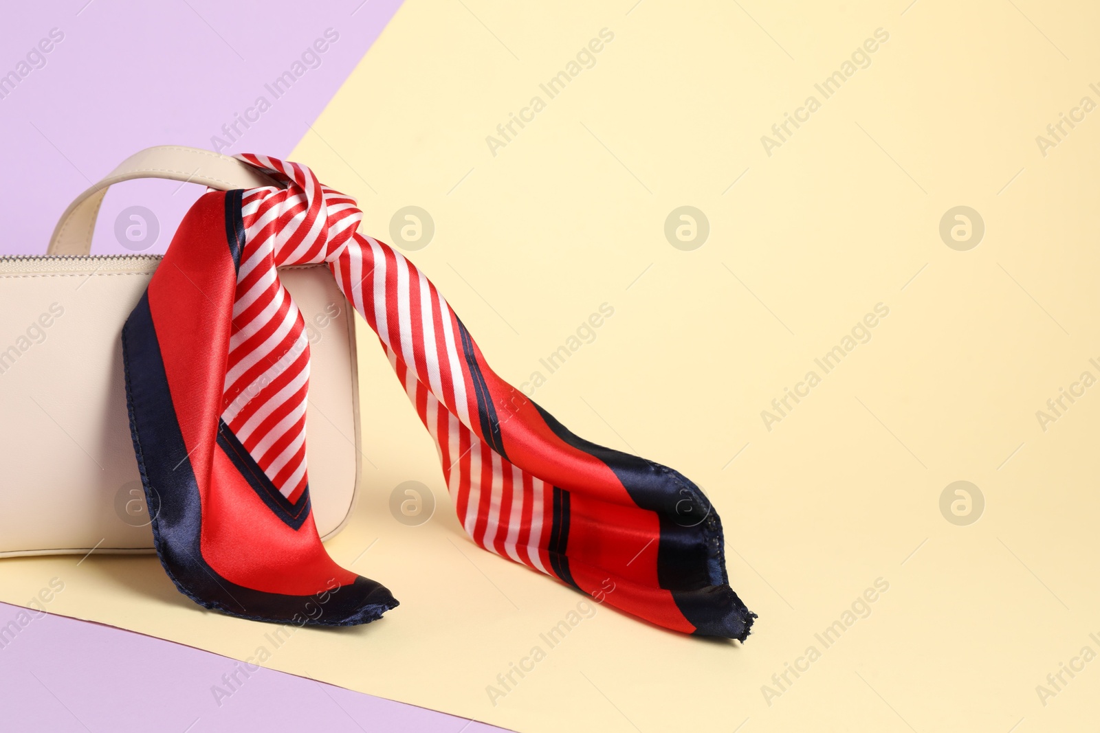 Photo of Handbag with striped scarf on color background. Space for text