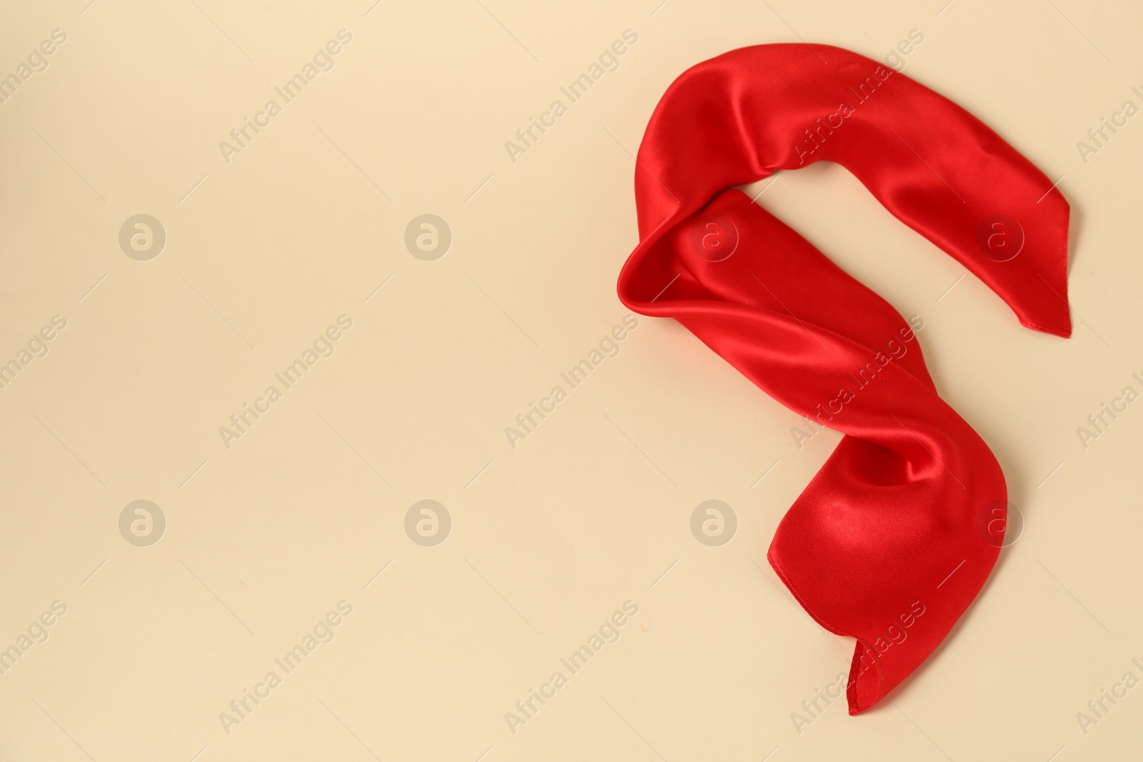 Photo of Beautiful red neck scarf on beige background, top view. Space for text