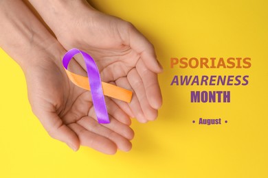 Image of Psoriasis Awareness Month (August). Woman holding orange-orchid awareness ribbon on yellow background, top view