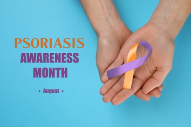 Image of Psoriasis Awareness Month (August). Woman holding orange-orchid awareness ribbon on light blue background, top view