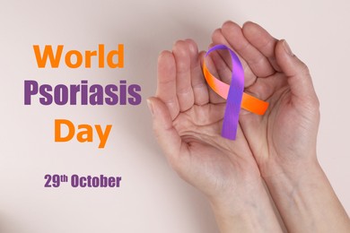 Image of World Psoriasis Day (October, 29). Woman holding orange-orchid awareness ribbon on light background, top view