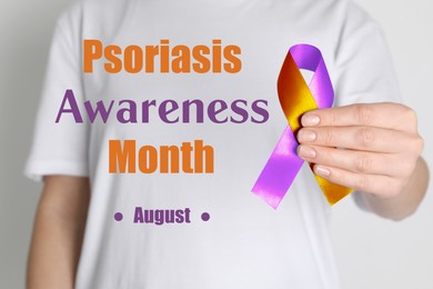 Image of Psoriasis Awareness Month (August). Woman holding orange-orchid awareness ribbon on white background, closeup