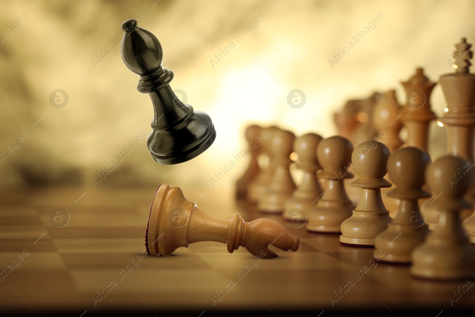 Image of Chess game. Black bishop beating white bishop in air over chessboard