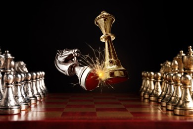 Image of Chess game. Golden queen beating silver knight in air over chessboard