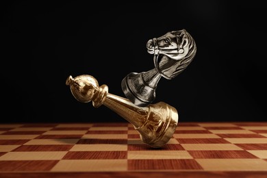 Image of Chess game. Silver knight beating golden bishop on chessboard