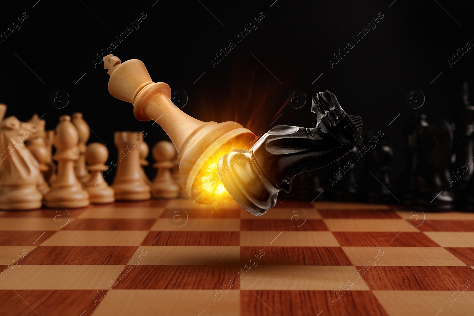 Image of Chess game. White king beating black knight in air over chessboard