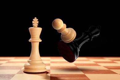 Image of Chess game. White pawn beating black king in air over chessboard