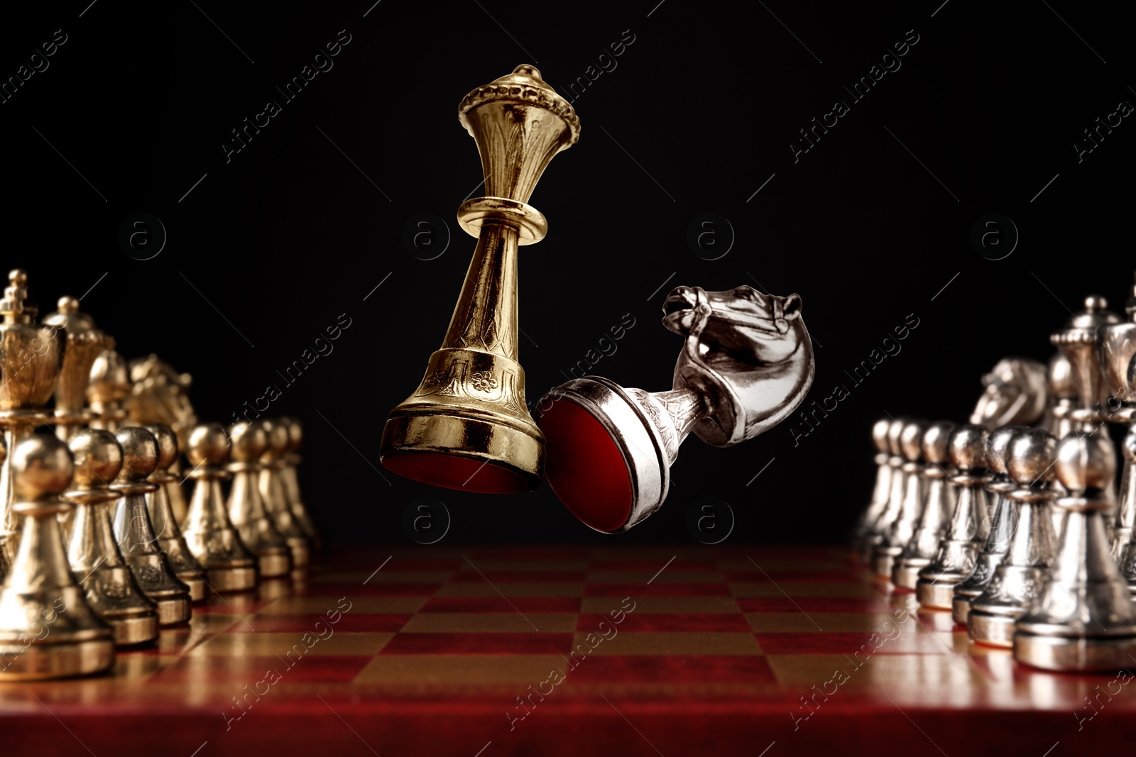 Image of Chess game. Golden queen beating silver knight in air over chessboard