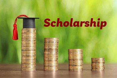 Image of Scholarship. Stacked coins and graduate hat on wooden table