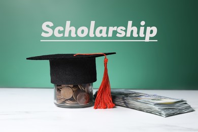 Image of Scholarship. Graduate hat, dollar banknotes and coins on white table