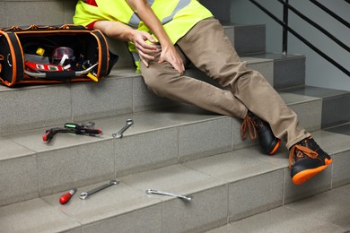 Photo of Accident at work. Man with injured leg on stairs indoors, closeup