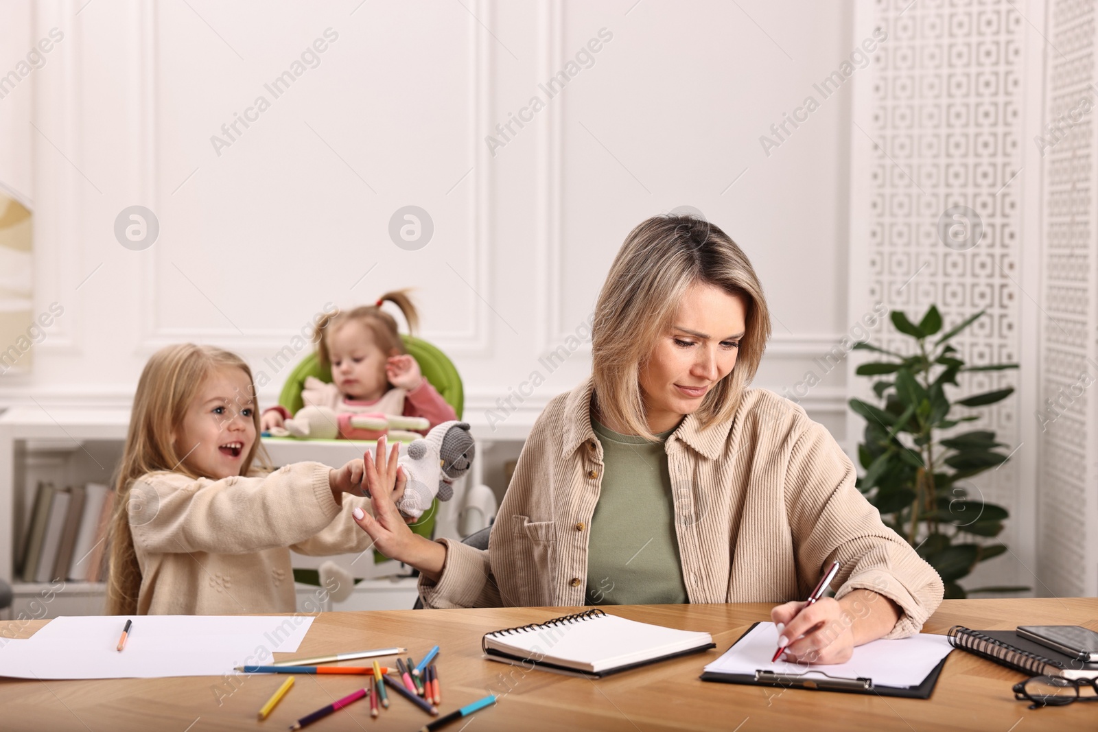 Photo of Single mother working and refusing to play with her daughter at wooden table indoors