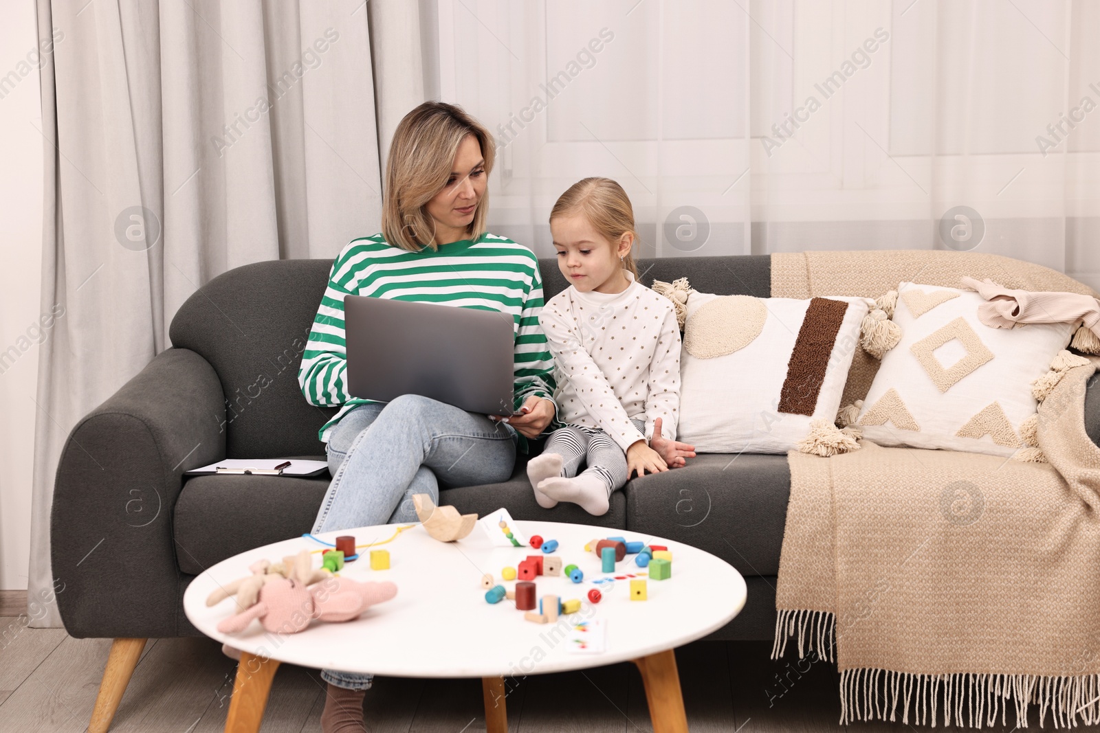 Photo of Work at home. Single mother with her daughter on sofa indoors