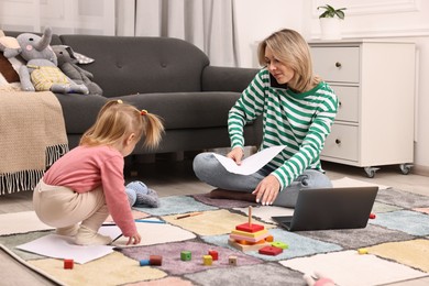 Photo of Work at home. Single mother talking by smartphone and her daughter on floor indoors