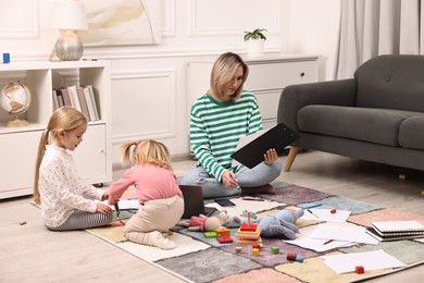 Photo of Single mother working and her children playing on floor at home