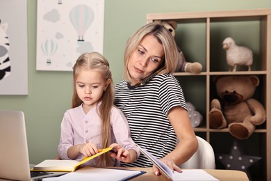 Work-family balance. Single mother talking by smartphone and her daughter at table in child's room